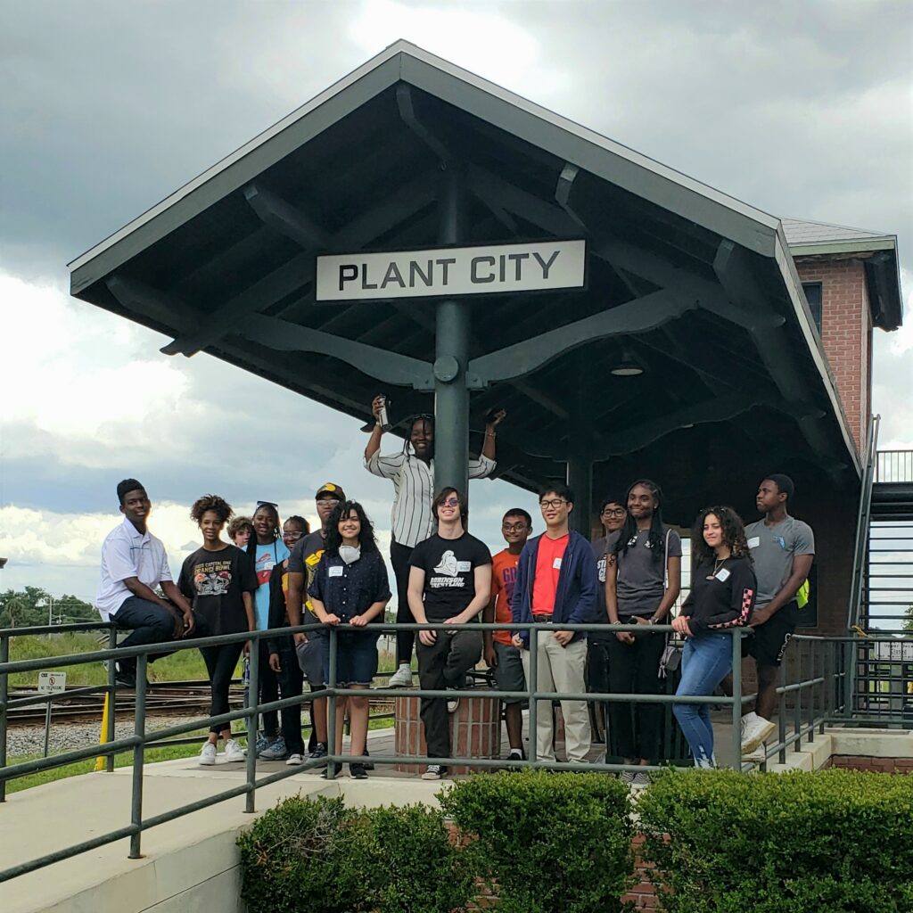 Group of diverse flip students posing for photo at the Plant City train depot