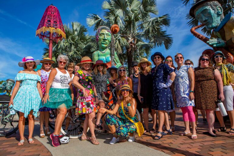 Women in fancy clothing pose in front of public art in Tampa
