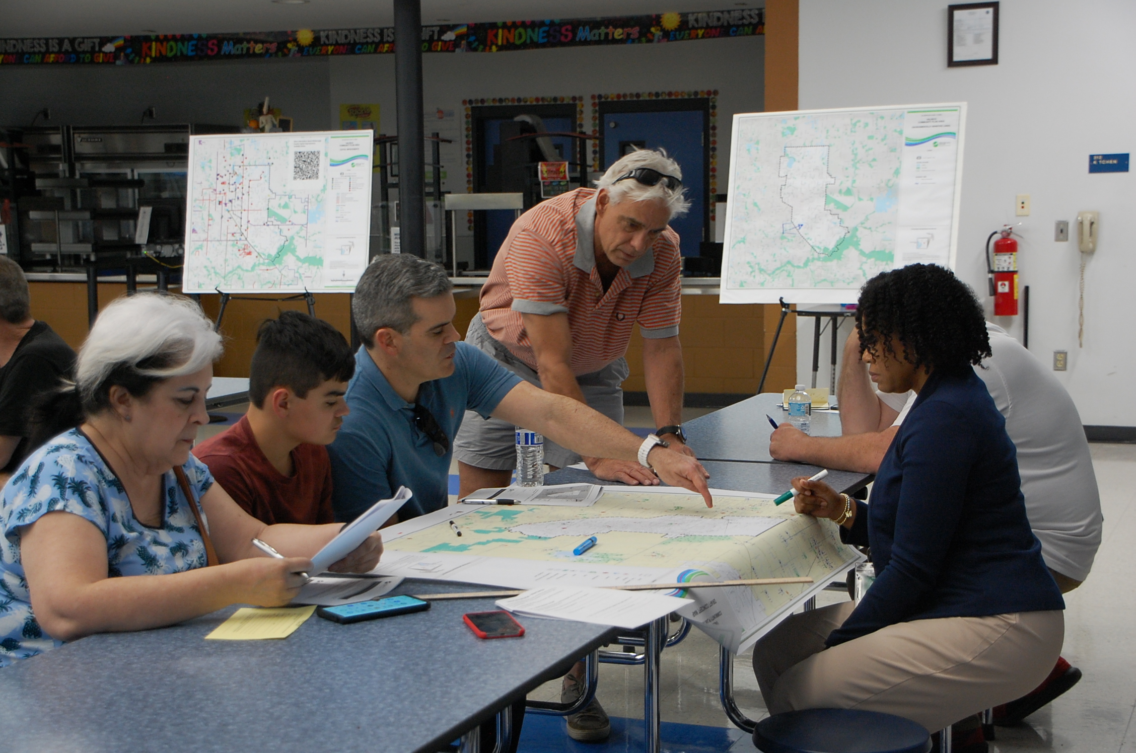 Community members gathered around a cafeteria table discussing a map of Valrico.