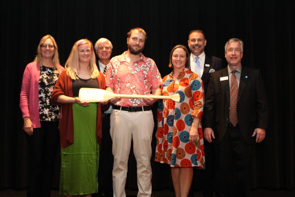 Hillsborough River Board Stewardship award winners stand with their paddle award on stage